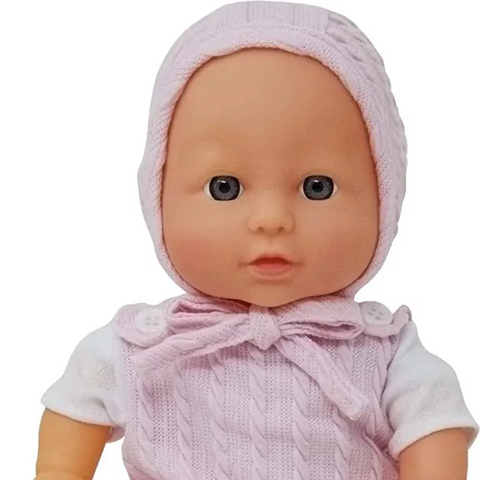 Baby doll wearing a pink knitted outfit with a white shirt on a white background