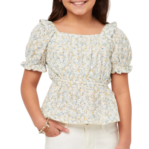 Girl wearing a smocked floral top with puff sleeves, ruffle trim, and a fitted peplum-style waist.
