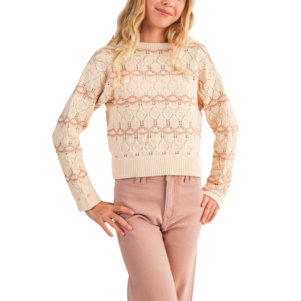 Tween girl wearing a cream wavy pointelle knit sweater with ribbed hem, cuffs, and round neckline