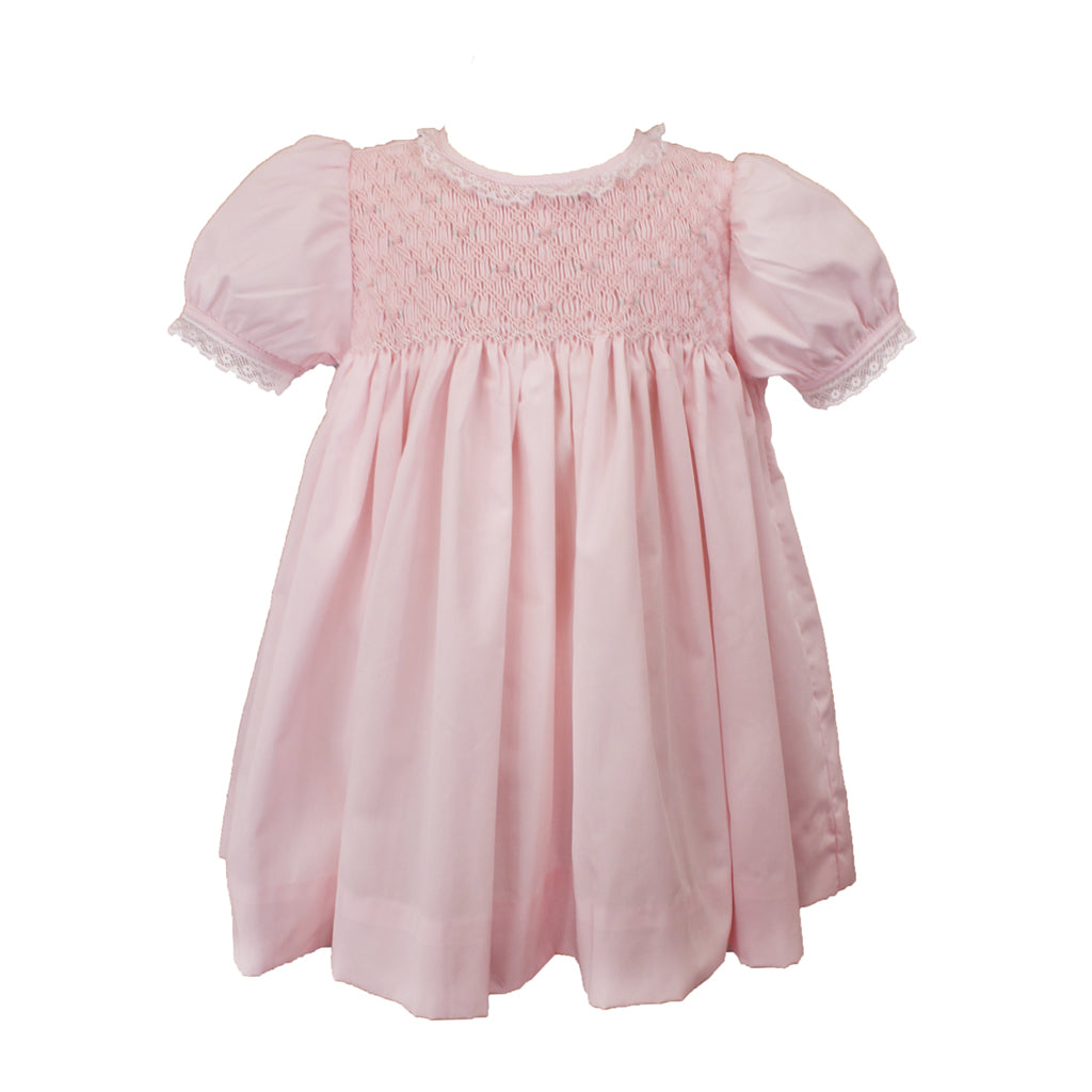 pink dress with a fully smocked top with roses, a lace outline on the neckline, and a lace sleeve line. 
