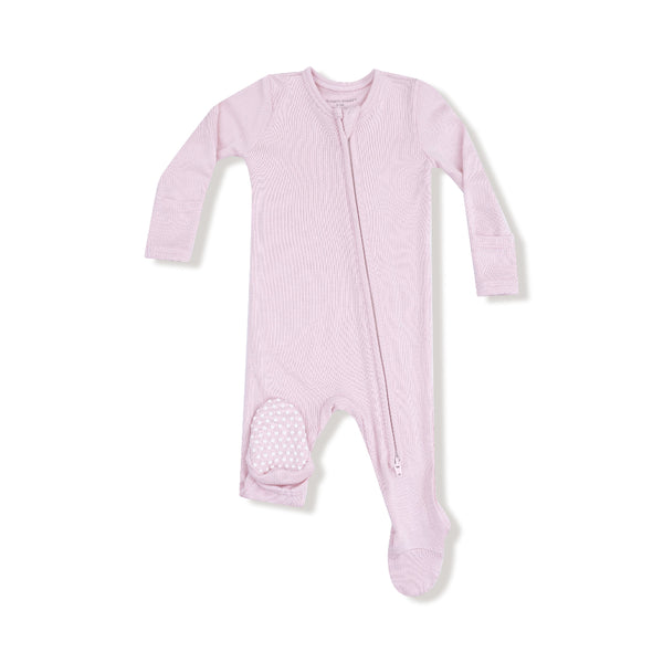 Blush pink baby footie made of ribbed bamboo fabric, featuring a two-way zipper, fold-over cuffs, and white polka-dot grippy feet.

