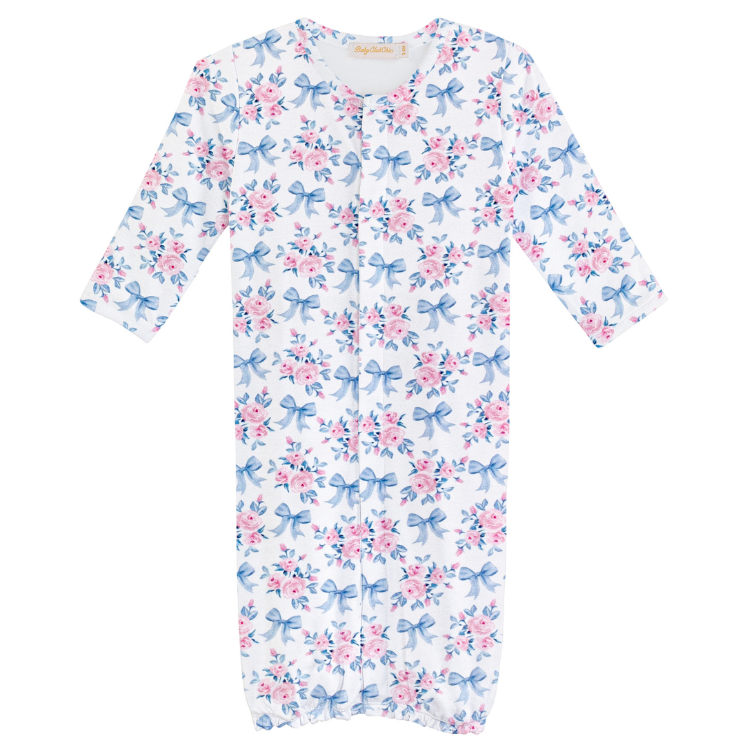 White baby gown with allover pink floral and blue bow print, featuring long sleeves and elastic bottom for easy diaper access.