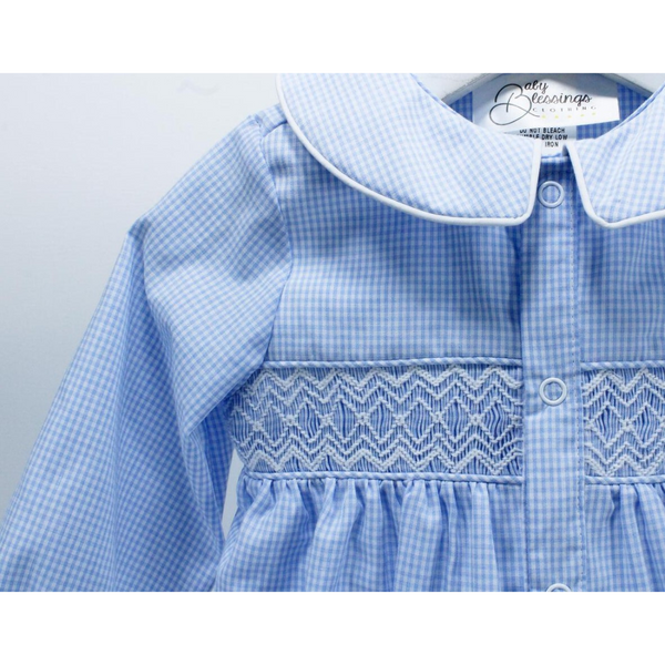 Close-up of the geometric smocking and collar detailing on the blue gingham romper, showing fine embroidery and snap buttons.