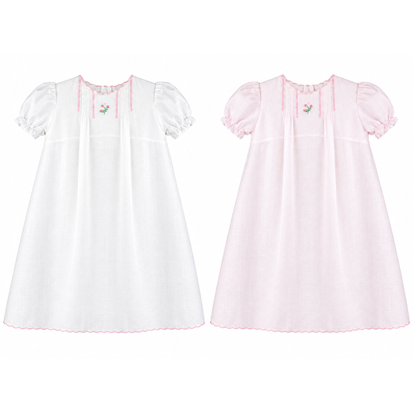 Pale pink and white girls’ dresses with rosebud embroidery, pintuck detailing, short puff sleeves and a pink scalloped hem.