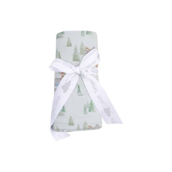 Buck Deer swaddle blanket with watercolor forest print, folded and tied with ribbon.










