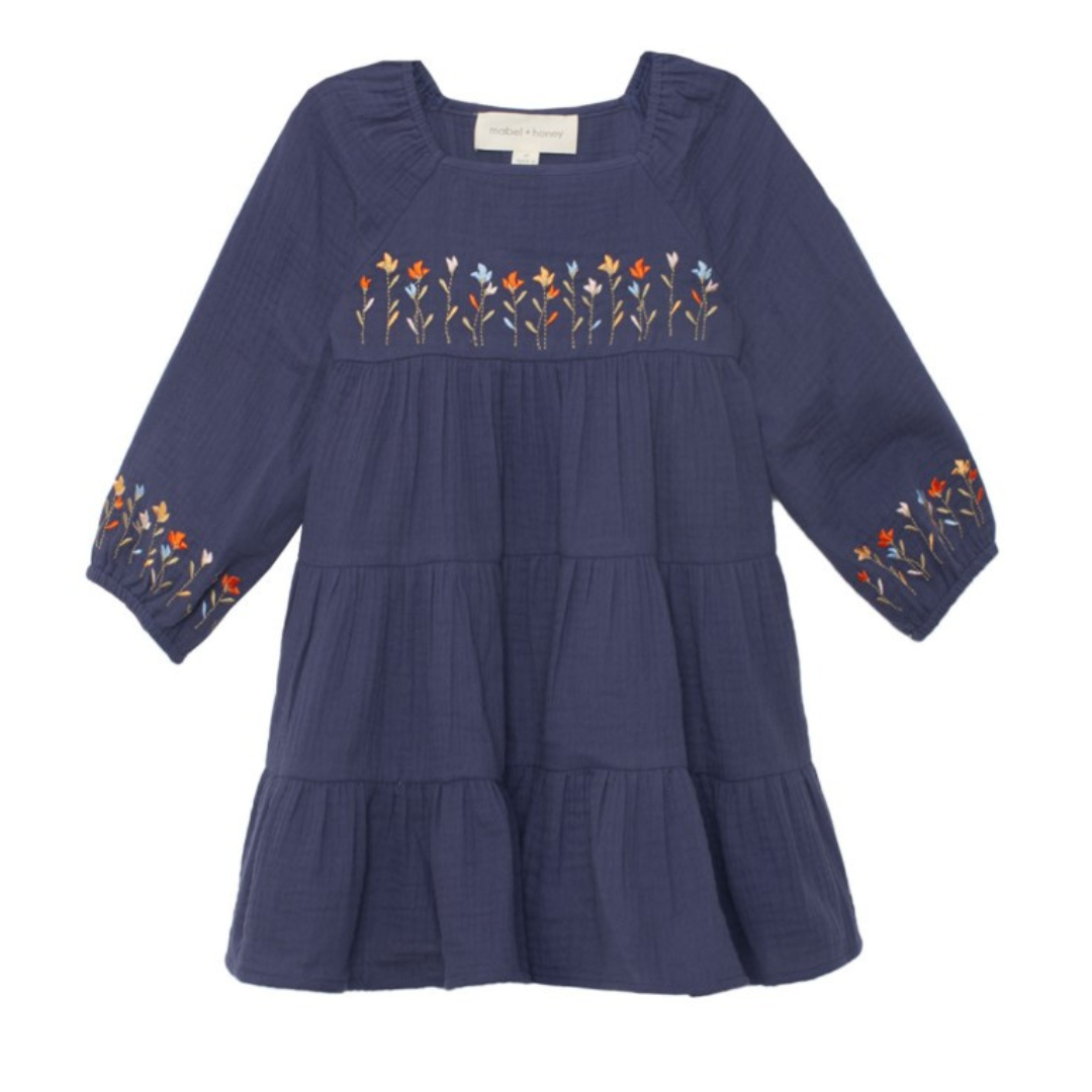 Flat lay front view of navy dress featuring floral embroidery across the chest and on puff sleeve cuffs.