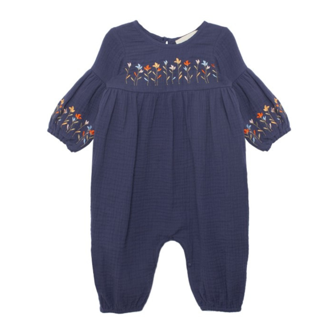 Navy baby romper with gathered tiers and embroidered flowers across the chest and sleeve cuffs.