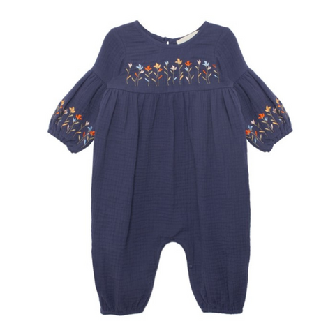 Navy baby romper with gathered tiers and embroidered flowers across the chest and sleeve cuffs.