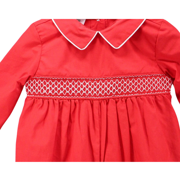Close-up of white geometric smocking design on red fabric with piped collar and pleated gathering below.