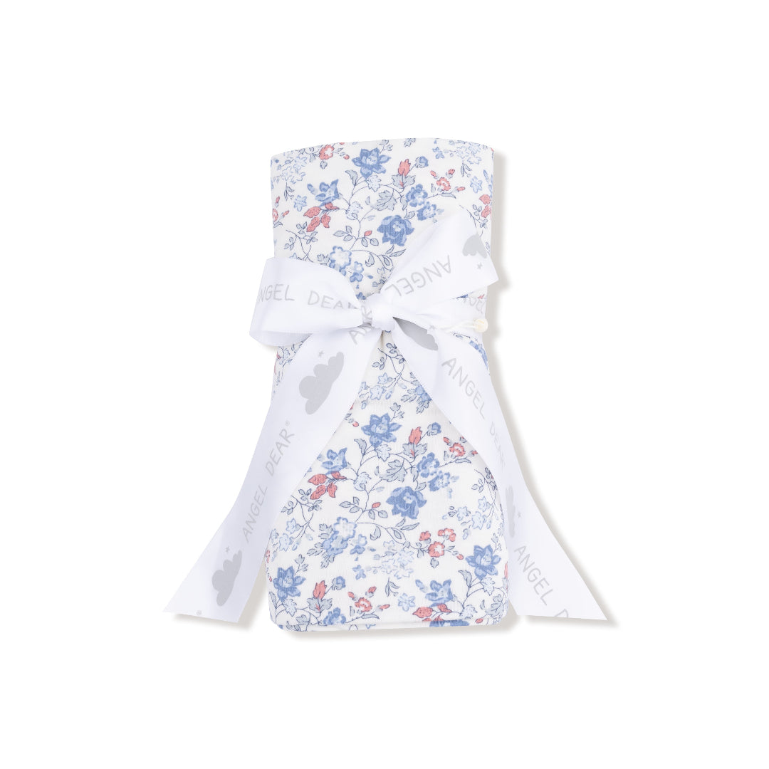 Country floral swaddle blanket with vintage-style blue and pink flower print on white background, partially rolled. 









