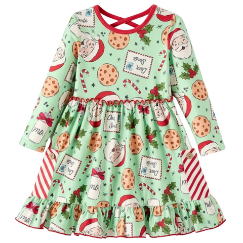 A long-sleeved girls' dress with a mint green background featuring a festive print of Santa Claus faces, chocolate chip cookies, candy canes, milk bottles, and "Dear Santa" letters. The dress has a red trim, a criss-cross back, a ruffled hem, and red and white striped pockets with button details.
