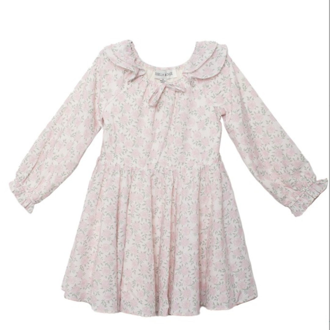 Light pink floral long-sleeve dress with ruffle cuffs and a gathered neckline, laid flat with skirt flared.