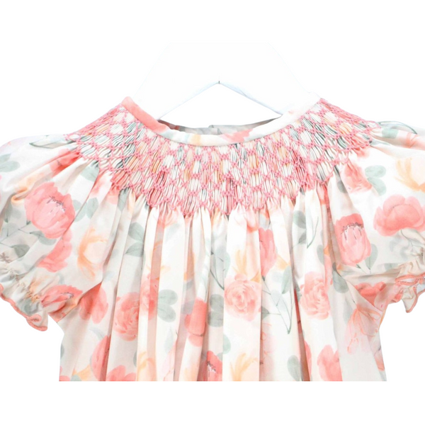 Close-up of pink hand-smocked detail on the neckline of a girl's floral dress