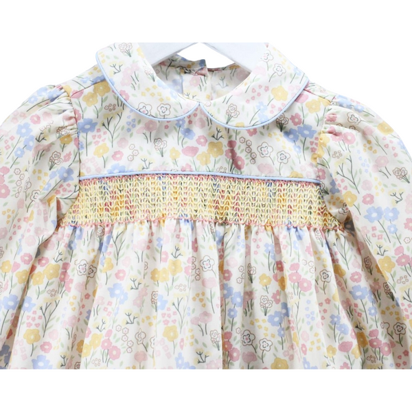 Close-up of the hand-smocked bodice and Peter Pan collar trimmed in blue on the floral dress.