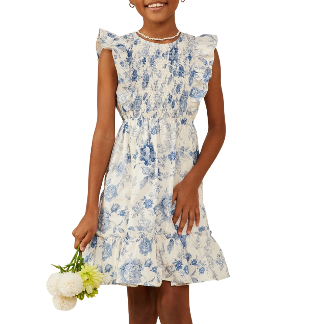 Girl in blue floral smocked dress with ruffle sleeves and tiered hem