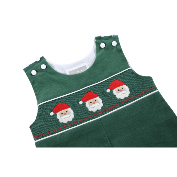 Close-up of green corduroy overalls showing detailed smocking with three embroidered Santa faces and white piping along the chest.
