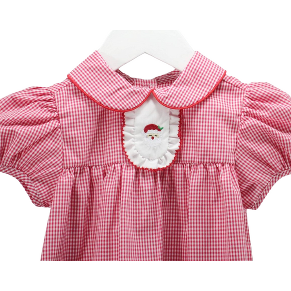 Close-up of embroidered Santa face on white ruffle bib, with red gingham fabric and piped collar detail.