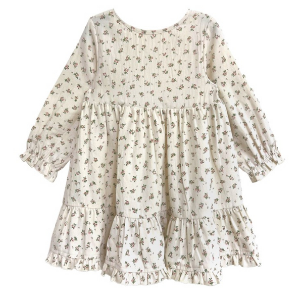 Back view of a cream-colored girls’ dress with a pink floral print and tiered ruffle hem.
