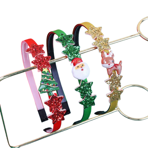 Three thin Christmas-themed headbands hanging on a gold metal rack. The first is red with a Christmas tree and red glitter stars. The second is green with a Santa Claus head and green glitter stars. The third is gold with a reindeer and gold glitter stars.