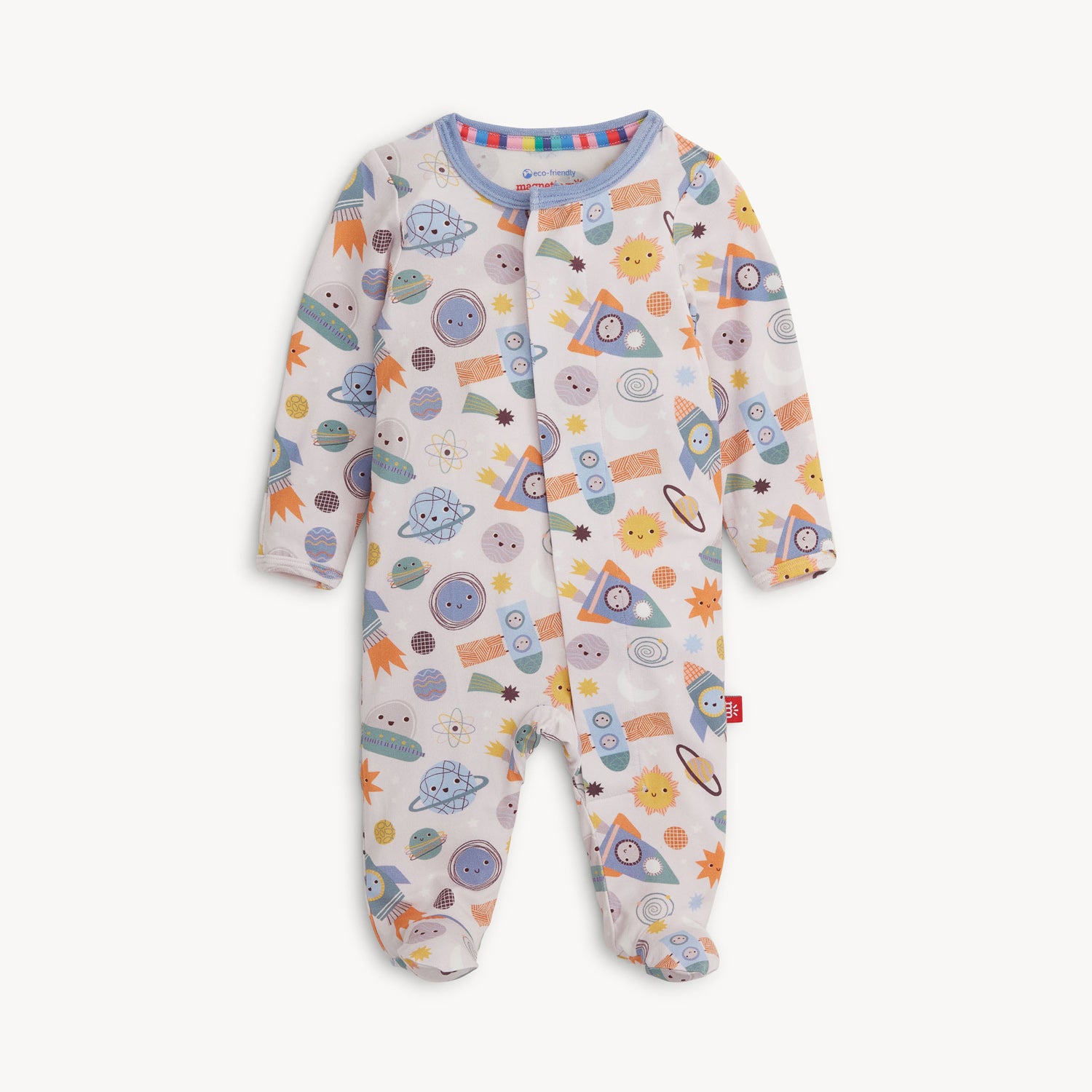 A full-length view of a white baby footie pajama with a "Let's Rocket" space-themed pattern. The pattern features cartoon-style planets, suns, stars, comets, and spaceships in shades of orange, yellow, blue, and green. The one-piece pajama has long sleeves, covered feet, and a full front opening with magnetic closures. A blue trim lines the collar and front opening. A small rainbow stripe is visible on the inner collar, and a red logo tag is sewn onto the lower right side.