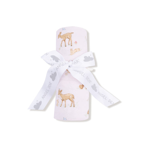 Blush pink swaddle blanket with adorable fawn and bunny print, folded with a white ribbon and shown unrolled for full pattern display.

