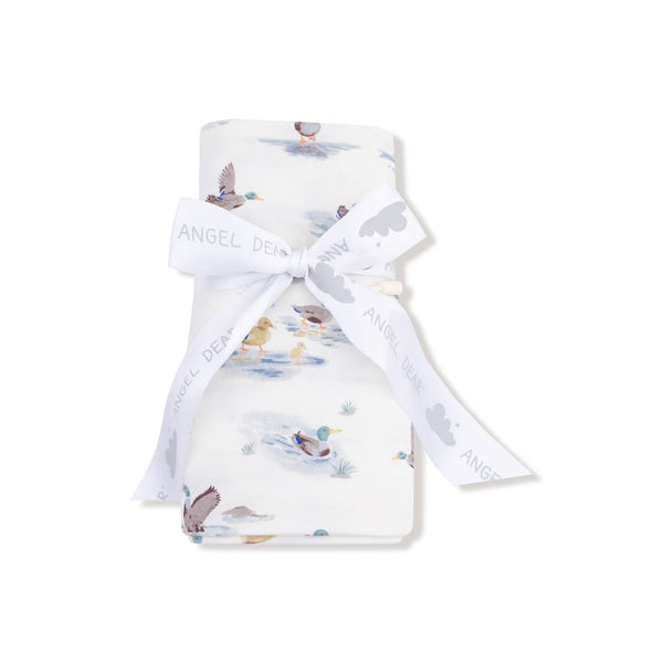 Swaddle blanket rolled and tied with a branded ribbon, mallard print visible