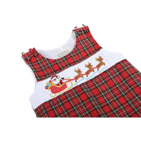 Detailed close-up of the smocked Santa in a sleigh with three reindeer embroidered on the white chest panel of red plaid overalls.

