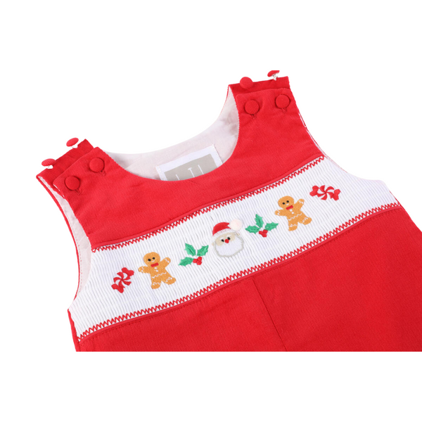 Close-up of red baby overalls showing smocked Christmas designs including Santa, holly, and gingerbread men on a white chest panel.