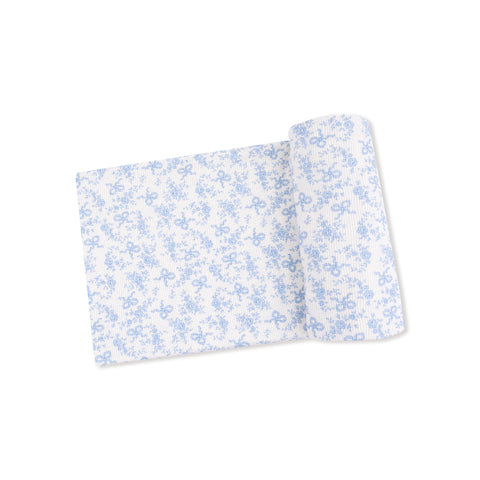 Swaddle blanket partially rolled and laid flat, featuring a blue floral and bow print on a white background with subtle stripe texture.









