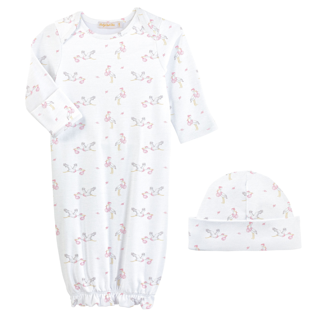 White baby gown and hat set featuring a pink stork print, long sleeves, and an elastic hem, made from soft cotton for newborn comfort.
