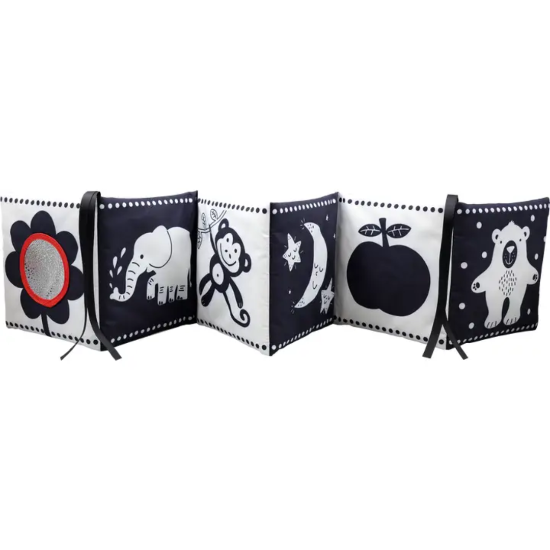 A black and white soft cloth baby book is shown in an accordion style, featuring a sheep, a cloud, an octopus, a dolphin, a cat, a bear, a flower with a mirror, an elephant, a monkey, a moon and stars, and an apple.