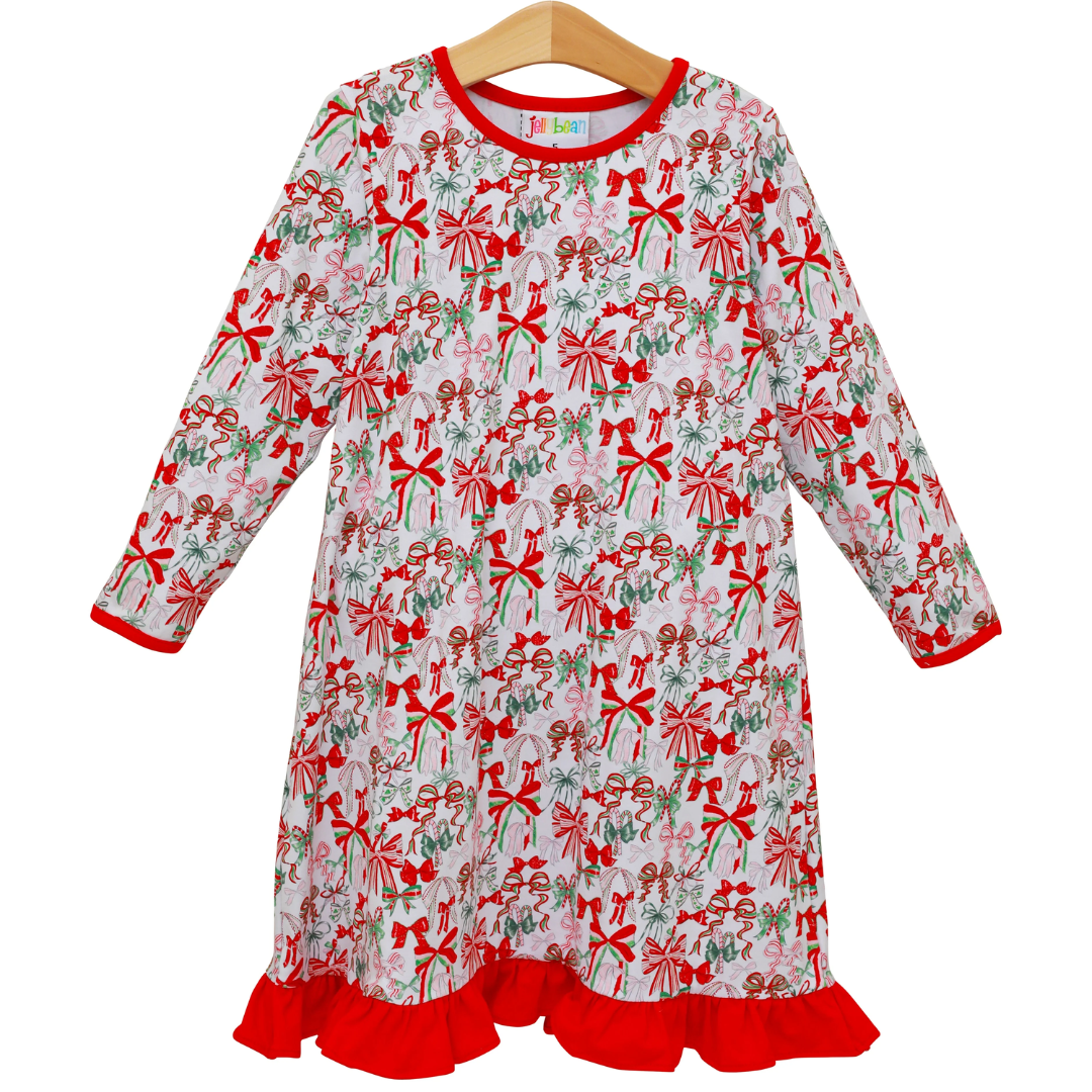 Little girl’s holiday dress with colorful Christmas bow print, red ruffle trim, and long sleeves.