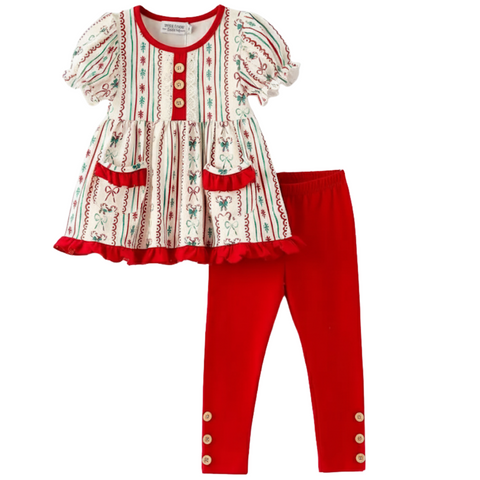  A two-piece girls' outfit featuring a white short-sleeve tunic top with red and green stripes, bows, and candy cane patterns, red ruffled pockets, and wooden buttons. It is paired with solid red leggings with wooden buttons at the ankles.