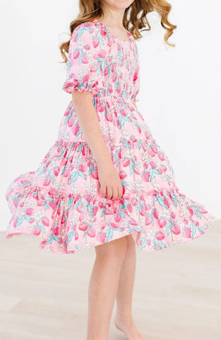 A pink dress with strawberries, a smocked front, rouched short sleeves, and a flowy skirt.